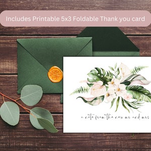 May include: A white thank you card with a watercolor illustration of tropical leaves and flowers. The text "a note from the new mr and mrs." is written in black cursive. The card is sitting on a wooden surface with a green envelope and a wax seal.