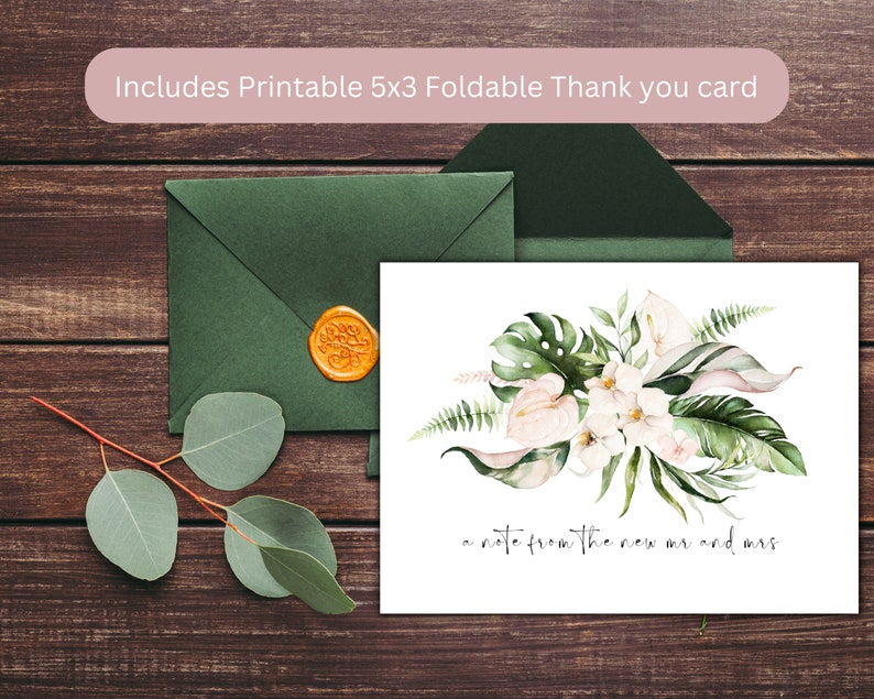 May include: A white thank you card with a watercolor illustration of tropical leaves and flowers. The text "a note from the new mr and mrs." is written in black cursive. The card is sitting on a wooden surface with a green envelope and a wax seal.