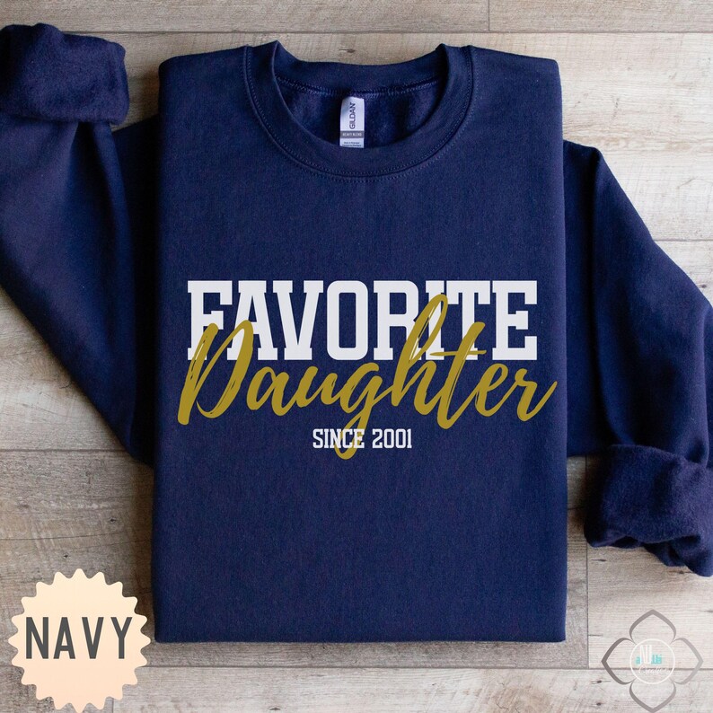 Puede incluir: Sudadera azul marino con las palabras "FAVORITE Daughter" en letras blancas y doradas. El texto "SINCE 2001" est&aacute; debajo de la palabra "Daughter". La sudadera tiene cuello redondo y mangas largas.