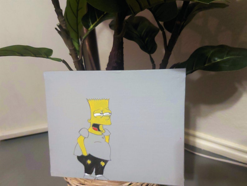 May include: Hand-painted canvas artwork featuring a yellow cartoon character with a mischievous expression. The character is wearing a grey shirt and black pants. The background is a light grey.