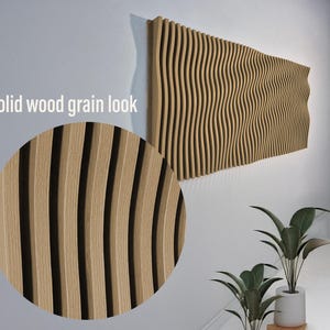 Op de afbeelding: Een close-up van een houten wandpaneel met een golvend patroon. Het paneel is gemaakt van lichtbruin hout en heeft een natuurlijke houtnerf. Het paneel is gemonteerd op een witte muur.
