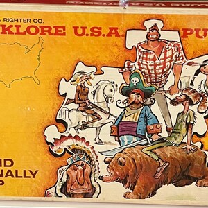May include: Vintage "Folklore U.S.A. Puzzle" box featuring a map of the United States and illustrations of American folklore characters. The box has a yellow background with the text "Selchow & Righter Co." and "Official Rand McNally Map".