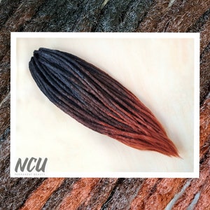 Puede incluir: Dreadlocks sintéticas ombre en negro y cobre. Las dreadlocks son largas y rectas, con una transición gradual del negro al cobre.