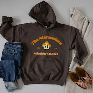 May include: A brown hooded sweatshirt with the text "The Marauders 1971 1978 Mischief Makers" and a graphic of three orange mushrooms.