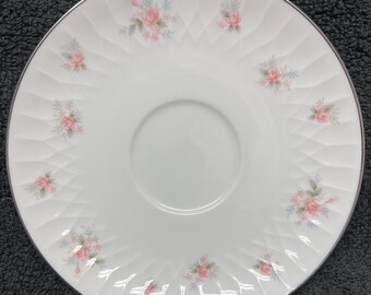 May include: White porcelain saucer with a silver rim and a delicate floral pattern featuring pink roses and green leaves.