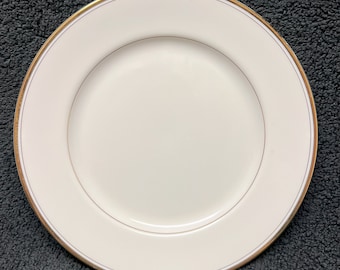 May include: A white ceramic dinner plate with a thin gold rim.