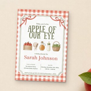 May include: A rectangular baby shower invitation with a red and white gingham border. The text reads Baby, you're the APPLE OF OUR EYE, a baby shower for Sarah Johnson, with location, date, and RSVP details. Illustrations include apples, a bonnet, a bottle, and a basket.
