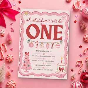 May include: A rectangular birthday invitation card with a scalloped pink border, featuring the text 'oh what fun it is to be ONE' in red, a string of ornaments, a pink Christmas tree, a cake, and event details for Eliana's first birthday.