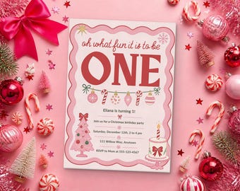 May include: A rectangular birthday invitation card with a scalloped pink border, featuring the text 'oh what fun it is to be ONE' in red, a string of ornaments, a pink Christmas tree, a cake, and event details for Eliana's first birthday.