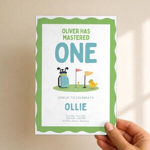May include: A rectangular invitation card with a green scalloped border. The text reads: OLIVER HAS MASTERED ONE, JOIN US TO CELEBRATE OLLIE, Saturday, June 14th, 11:00 AM - 2:00 PM, 123 Main Street, Anytown. Features a golf bag, flag, and bird.