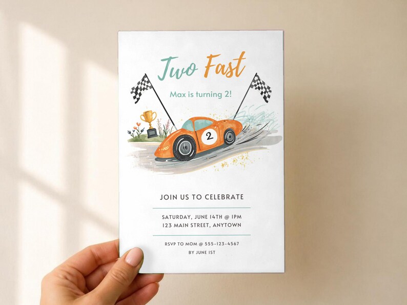 May include: A rectangular birthday invitation card featuring an orange race car with the number 2, two checkered flags, and a gold trophy. The text reads Two Fast, Max is turning 2!, JOIN US TO CELEBRATE, SATURDAY, JUNE 14TH @ 1PM, 123 MAIN STREET, ANYTOWN, RSVP TO MOM @ 555-123-4567 BY JUNE 1ST.