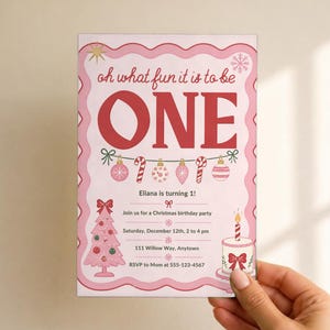 May include: A rectangular birthday invitation card with a pink scalloped border. The text reads: oh what fun it is to be ONE, Eliana is turning 1!, Join us for a Christmas birthday party, Saturday, December 12th, 2 to 4 pm, 111 Willow Way, Anytown, RSVP to Mom at 555-123-4567. Features a pink Christmas tree, cake, and ornaments.