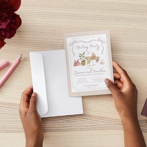 May include: A rectangular invitation card with a beige striped border and a white center featuring the text Nesting Party, Simone and Jonathan, and illustrations of a baby cradle, a potted plant, a teddy bear, and a baby hat.