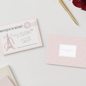 May include: A light pink baby shower invitation card featuring the text BONJOUR B&Eacute;B&Eacute;, an Eiffel Tower illustration with a bow, and a postage stamp graphic. A matching pink card with vertical stripes and a central white label is also shown.