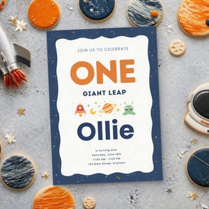 Könnte beinhalten: Eine rechteckige Geburtstagseinladungskarte mit dunkelblauem Rand und Sternen, weißer Mitte, orangefarbenem Text ONE, GIANT LEAP, kleinen Weltraum-Symbolen und dem Namen Ollie in Dunkelblau sowie den Veranstaltungsdetails darunter.