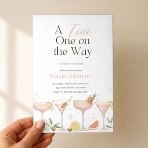 May include: A rectangular baby shower invitation card with white background and black and pink text reading A Tini One on the Way Mocktails & Brunch honouring Sarah Johnson. The bottom features watercolour illustrations of four pink cocktails.