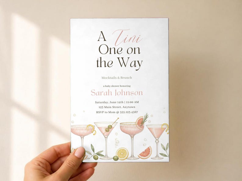 May include: A rectangular baby shower invitation card with white background and black and pink text reading A Tini One on the Way Mocktails & Brunch honouring Sarah Johnson. The bottom features watercolour illustrations of four pink cocktails.