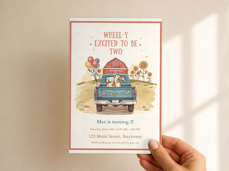 May include: A rectangular birthday invitation card featuring a blue pickup truck carrying a goat, balloons, and a red barn. The text reads: WHEEL-Y EXCITED TO BE TWO, Max is turning 2!, Saturday, June 14th, 11:00 AM - 2:00 PM, 123 Main Street, Anytown, RSVP to Mom @ 555.123.4567 by June 1st.