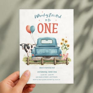 May include: A birthday invitation card featuring a blue pickup truck, a cow, a pig, and sunflowers behind a wooden fence. Text reads: Wheel-y Excited to Be ONE, Max is turning one, Saturday, June 14th, 11:00 AM - 2:00 PM, 123 Main Street, Anytown, RSVP to Mom @ 555.123.4567 by June 1st.