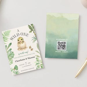 May include: Two rectangular cards featuring a baby dinosaur hatching from an egg, green tropical leaves, and the text A WILD ONE is on the way. The second card displays a QR code with the text REGISTERED AT AMAZON TARGET.