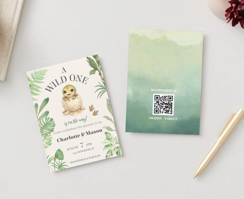 May include: Two rectangular cards featuring a baby dinosaur hatching from an egg, green tropical leaves, and the text A WILD ONE is on the way. The second card displays a QR code with the text REGISTERED AT AMAZON TARGET.