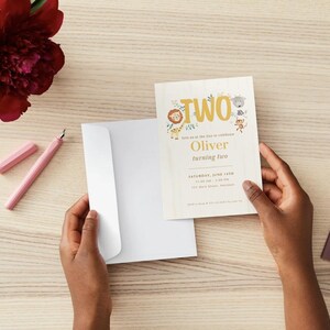 May include: A rectangular birthday invitation card featuring the word TWO in large gold letters, illustrated with a lion, giraffe, and monkey. The text reads Oliver turning two, Saturday, June 14th, 11:00 AM - 2:00 PM, 123 Main Street, Anywhere.