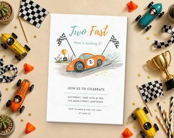 May include: A rectangular birthday invitation card featuring an orange race car with the number 2, checkered flags, and a gold trophy. The text reads: Two Fast, Max is turning 2!, JOIN US TO CELEBRATE, SATURDAY, JUNE 14TH @ 1PM, 123 MAIN STREET, ANYTOWN, RSVP TO MOM @ 555-123-4567 BY JUNE 1ST.