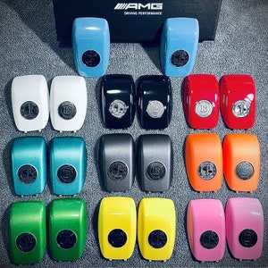 May include: A collection of 18 small, round, colorful keychains with a black and white logo. The keychains are arranged in three rows of six. The keychains are all different colors, including blue, red, orange, yellow, green, and pink. The keychains have a black and white logo that says "AMG Driving Performance".