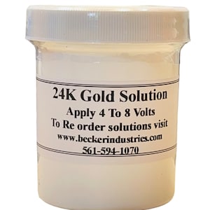 May include: A white plastic jar with a white lid containing a clear liquid. The label reads "24K Gold Solution", "Apply 4 To 8 Volts", "To Re order solutions visit www.beckerindustries.com", and "561-594-1070".