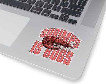 Puede incluir: Una pegatina troquelada con una ilustración detallada de un camarón rojo en el centro. El texto SHRIMPS IS BUGS está impreso en letras mayúsculas blancas, negritas y sin remates con un borde rojo grueso, dispuesto alrededor del camarón.
