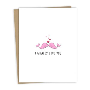 May include: A greeting card with two pink whales kissing with red hearts above them. The text on the card reads "I whaley love you."