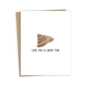 May include: A white card with a brown crepe illustration and the text "Love you a crepe ton".