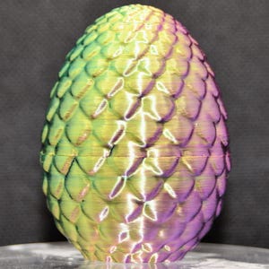 May include: A green, purple, and gold iridescent dragon egg with a scaly texture.