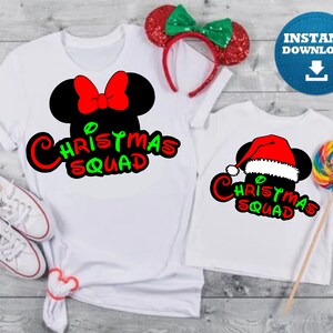 May include: Two white t-shirts with a Christmas Squad design featuring a Mickey Mouse head with a Santa hat and a bow. The design is in red, green, and black.