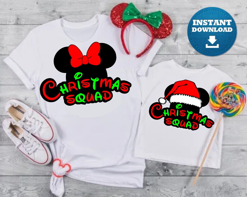 May include: Two white t-shirts with a Christmas Squad design featuring a Mickey Mouse head with a Santa hat and a bow. The design is in red, green, and black.