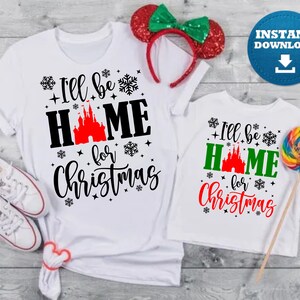 May include: Two white t-shirts with a Christmas themed design. The larger shirt has the text "I'll be home for Christmas" with a red castle graphic. The smaller shirt has the text "I'll be home for Christmas" with a green castle graphic.