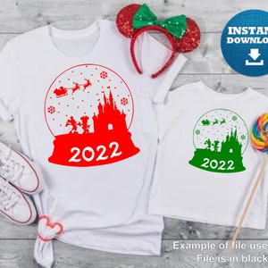 May include: Red and green Christmas-themed iron-on design featuring a snow globe with Mickey Mouse and friends in front of Cinderella's Castle. The design includes the text "2022".