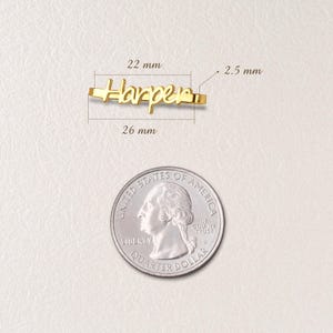 May include: Gold nameplate necklace with the name "Harper" in cursive script. The necklace is 26 mm long and 2.5 mm thick. A US quarter is shown for size comparison.