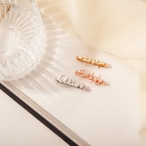 May include: Three personalized name necklaces in gold, rose gold, and silver. The names are "Harper", "Evelyn", and "Ocean".