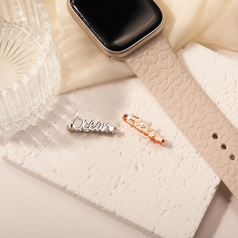 May include: Two personalized nameplate charms, one silver with the name "Ocean" and one rose gold with the name "Evelyn".