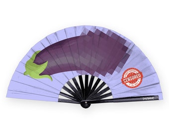 May include: A purple and green eggplant illustration on a lavender folding fan with a black handle. The fan has a red circular stamp that says "Adult Content Censored 18+ Only".