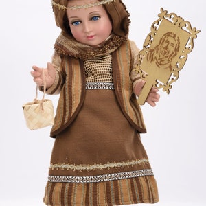 May include: A brown and gold doll dressed in a traditional outfit with a basket and a wooden plaque with a carved image of Jesus.
