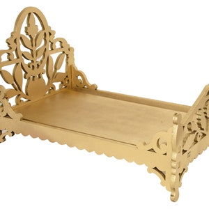 Puede incluir: Un marco de cama de madera de color dorado con intrincados tallados florales. El marco de la cama está diseñado con una cabecera y un piecero, y los bordes del marco son festoneados.