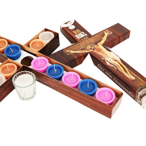 May include: A wooden cross with a depiction of Jesus Christ on the cross. The cross is decorated with a brown wood grain pattern. The cross is surrounded by small votive candles in various colors, including pink, blue, and white. The candles are arranged in a cross shape. The text "Doce velas Devocionales" is printed on the cross.