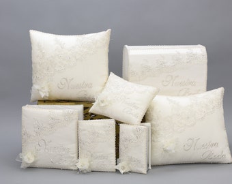May include: Set of white satin pillows and boxes with embroidered lace and the text "Nuestra Boda" which translates to "Our Wedding" in English.