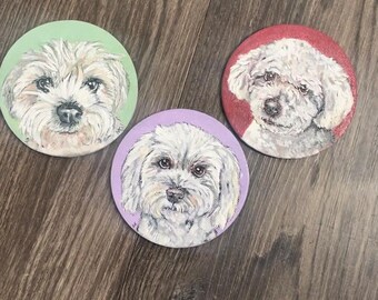 May include: Three round coasters featuring portraits of a fluffy white dog. Each coaster has a different pastel background: green, pink, and purple. The dog's face is centered on each coaster, with detailed fur and expressive eyes.