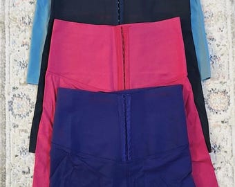 May include: Four pairs of high-waisted shorts in different colors: blue, black, red, and navy blue. Each pair has a zipper closure and a waistband with a row of hooks.
