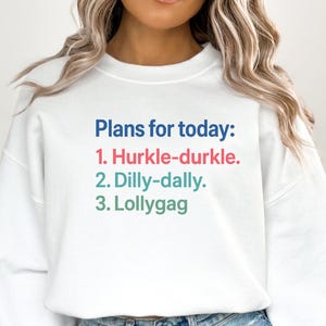 Könnte beinhalten: Weißes Sweatshirt mit dem Text "Plans for today: 1. Hurkle-durkle. 2. Dilly-dally. 3. Lollygag." Der Text ist in Blau, Rot und Grün gehalten. Das Sweatshirt hat einen lässigen Stil.