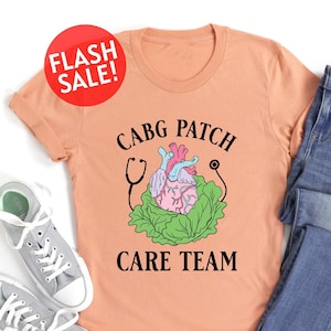 May include: A peach-colored t-shirt with the text "CABG PATCH CARE TEAM" in black. A cartoon heart with a stethoscope is inside a green lettuce.