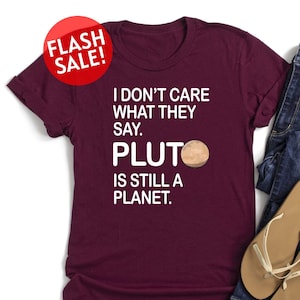 May include: A maroon t-shirt with white text that reads "I don't care what they say. Pluto is still a planet."